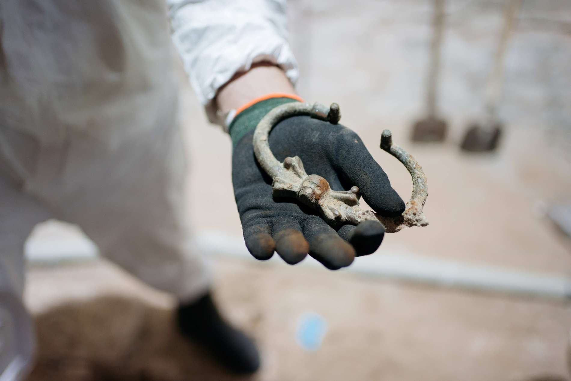 Het metalen handvat van een doodskist gedecoreerd met een schedel in de hand van een archeoloog die de vondst deed tijdens opgravingen in De Nieuwe Kerk