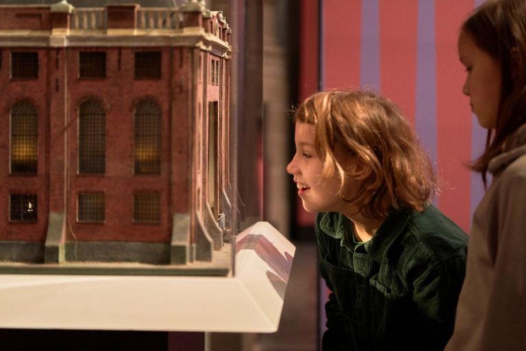 Twee kinderen kijken van dichtbij naar een miniatuur van de Portugese Synagoge in Amsterdam