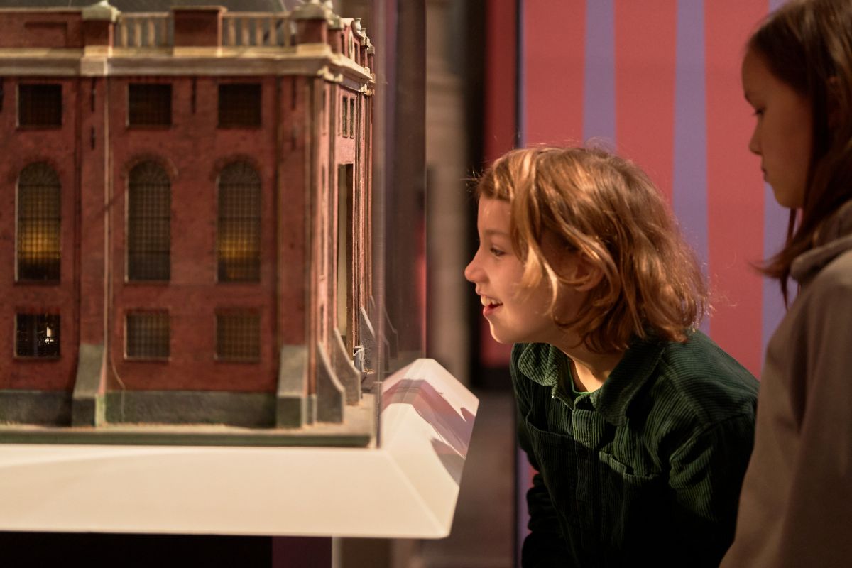 Twee kinderen kijken van dichtbij naar een miniatuur van de Portugese Synagoge in Amsterdam