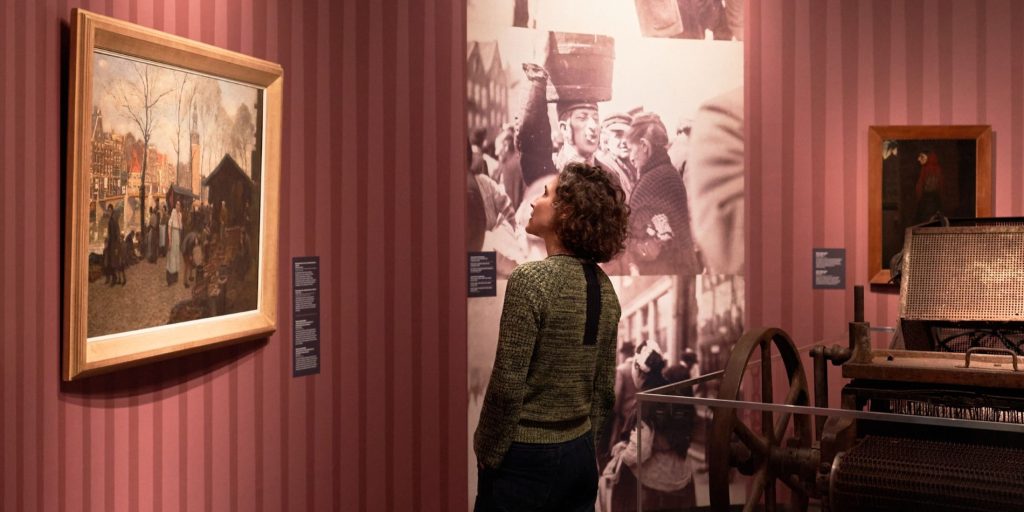Bezoeker kijkt naar schilderij in de tentoonstelling Mokum, de biografie van Joods Amsterdam